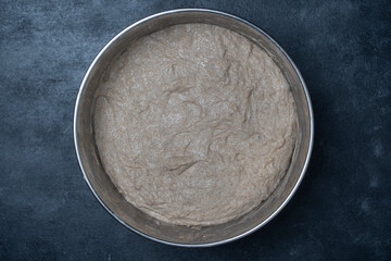 Rye sourdough dough for baking bread in a metal bowl, close up