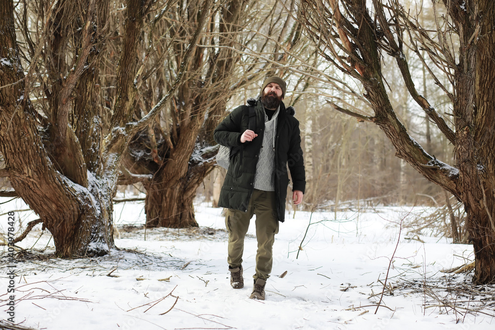 Wall mural outdoor portrait of handsome man in coat and scurf. bearded man in the winter woods.