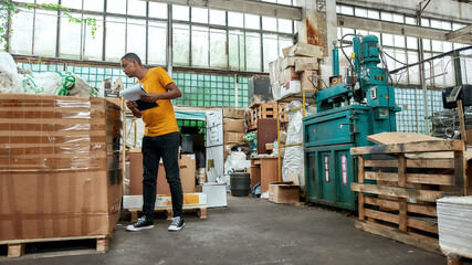 Young worker peeping into box on garbage station