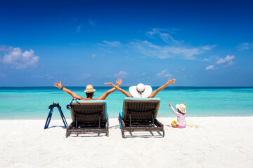 Happy family on sunbeds enjoys their vacation on a tropical beach with turquoise ocean and sunshine - Powered by Adobe