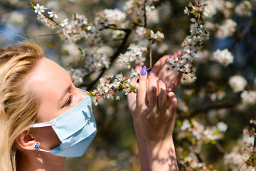 A girl in protective medical mask in spring among the blooming garden. . Spring allergy conception