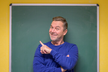 Male teacher pointing to the chalkboard behind him