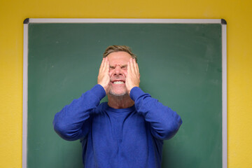 Exasperated teacher grimacing with hands to face