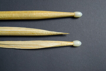 wooden drum sticks on a black background. one of the sticks is broken
