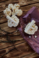  cauliflower pieces on wooden table and purple craft paper. High quality photo