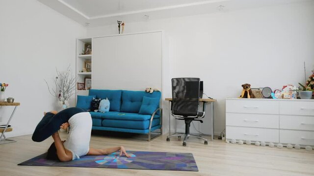 Young woman does yoga at home in matsyasana pose