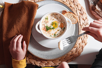 Cocotte egg for breakfast. Kid  hands. 