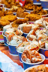 Food concept. Fresh grilled crab slices placed in paper bowls on counter in Thailand fresh food market. Center of image is in camera focus with shallow depth of field