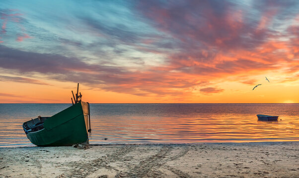 Anchored on sandy beach fishing boats near a small village of fishermen; here, at the Baltic Sea,  traditional and mighty Baltic fisheries was successfully developed in 19-20-th centuries