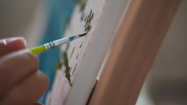 Close up paintbrush with acrylic paint. Woman painting a canvas with numbers