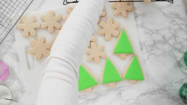 Flat lay. Stp by step. Icing Christmas tree-shaped sugar cookies with green royal icing.