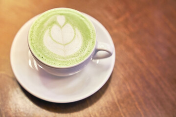 Cup of matcha latte on wooden background and a beige napkin in a cafe with copy space. High quality photo