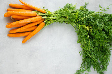 Carrots with tops on a grey concrete background