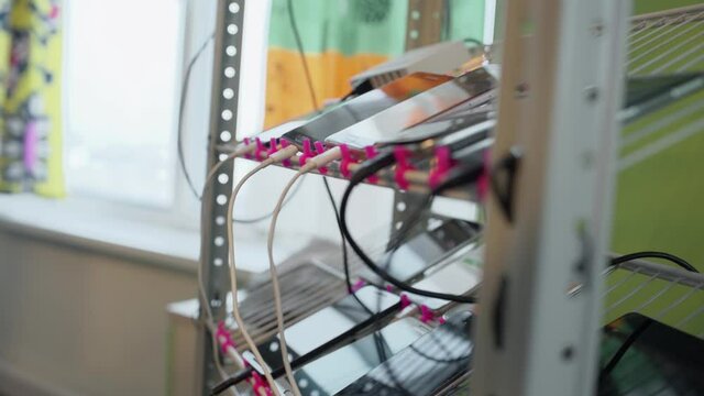 Lots of smartphones connected by wires lie on the shelf. Test bench for mobile phones or applications