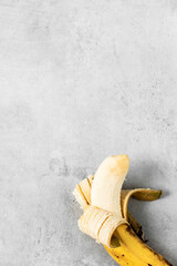 Peeled banana on a grey concrete background