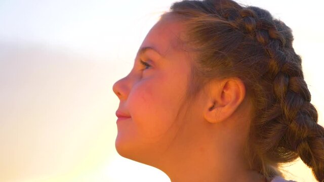 Beautiful portrait of a girl at sunset. A happy child enjoys fresh air, freedom. Children's meta. The concept of a happy family.