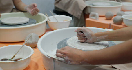 Female potter makes a pot on the pottery wheel