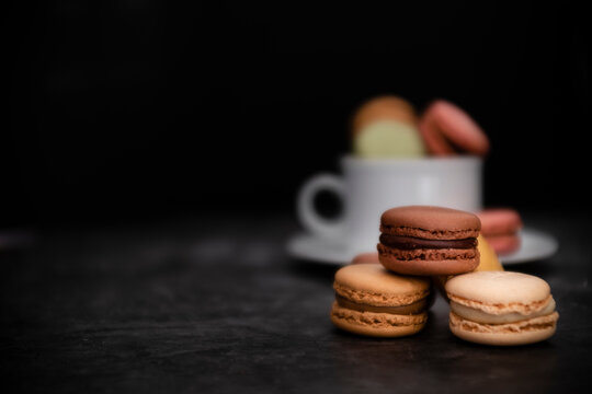 Macarons in tasse vor dunklem Hintergrund