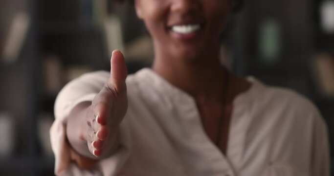 Out of focus happy african woman hold out her hand for handshake meets the client express respect feels confident, close up view to outstretched arm. Business, partnership, gesture of regard concept