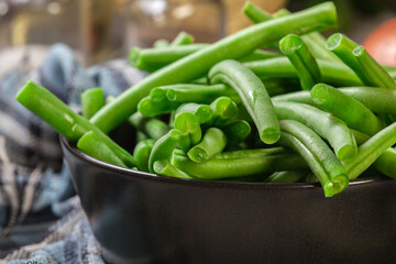 Raw green beans in a black dish - obrazy, fototapety, plakaty