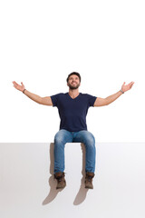 Happy Handsome Man Is Sitting On A Top With Arms Outstretched, Looking Up And Enjoying The View