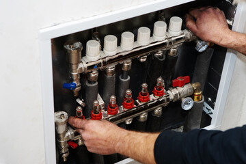 House heating system adjustment. A plumber is setting up automatic switchgear in a living space. Unrecognizable person. Close-up