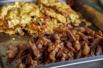 Fried meat with omelet in a tray