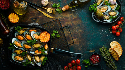 Frying pan with fried mussels with garlic, parsley, lemon and spices. On a black stone background. Free space for text.