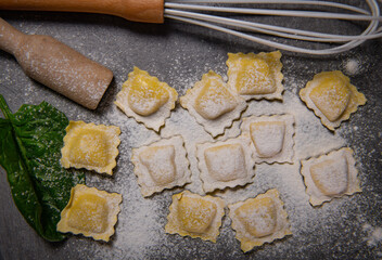 Tasty raw ravioli with flour and spinach on dark background, process of making italian ravioli, High quality photo