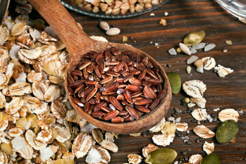 Oat flakes with brown rice, glass jar of green buckwheat, chia and pumpkin seeds on a wooden background.