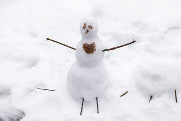 Sad snowman with iced heart in winter park