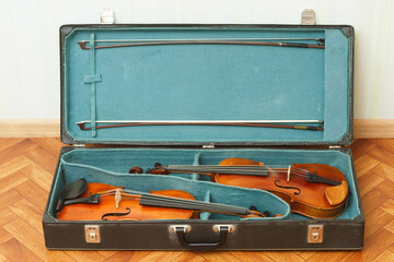Two classical violins with bows in a double case
