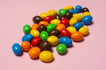 Colorful chocolate dragee on pink background  