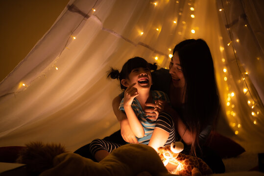 Happy mother and daughter playing at home in tent . family bedtime before asleep.