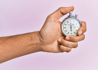 Hand of young hispanic man using stopwatch over isolated pink background. - obrazy, fototapety, plakaty