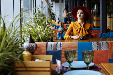 sad girl in a yellow dress and a hat sits in a cafe, pandemic, isolation.