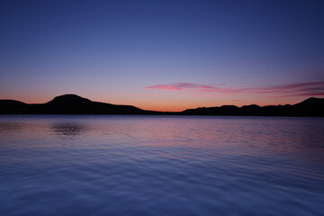 夜明けの湖の上に広がる鮮やかな空。屈斜路湖、北海道、日本。
