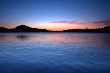 夜明けの湖の上に広がる鮮やかな空。屈斜路湖、北海道、日本。