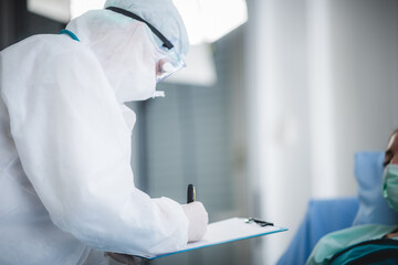 professional doctors in the full protective suits and surgical masks are examining the infected patient in the hospital control area