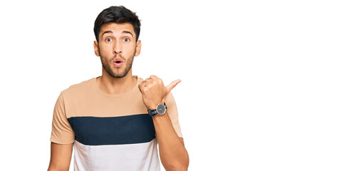Young handsome man wearing casual clothes surprised pointing with hand finger to the side, open mouth amazed expression.