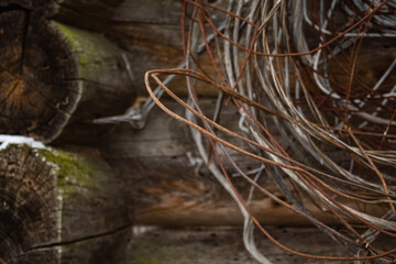 Many kinds of wire hangs on a nail on the wall of a wooden structure in the village