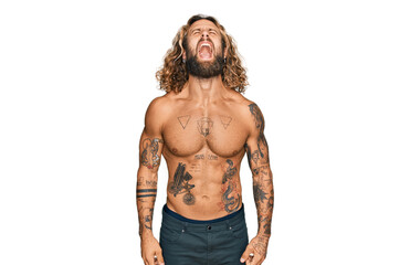 Handsome man with beard and long hair standing shirtless showing tattoos angry and mad screaming frustrated and furious, shouting with anger. rage and aggressive concept.