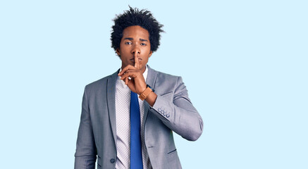 Handsome african american man with afro hair wearing business jacket asking to be quiet with finger...