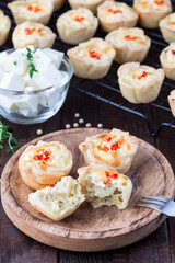 Feta cheese and fried onion mini quiche muffins, on wooden plate and cooling rack, vertical