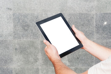 Close-up tablet mockup with a white screen in the hands of a businessman against the background of a concrete wall.