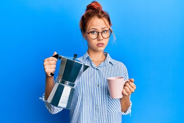 Young redhead woman drinking italian coffee skeptic and nervous, frowning upset because of problem. negative person.