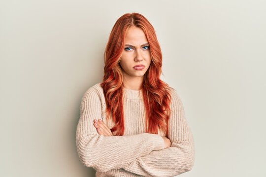 Young beautiful redhead woman wearing casual winter sweater skeptic and nervous, disapproving expression on face with crossed arms. negative person.