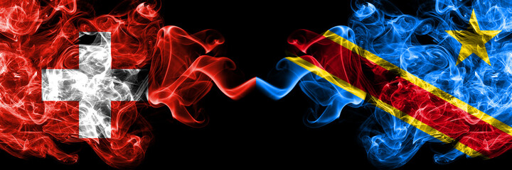 Switzerland, Swiss vs Democratic Republic of the Congo smoky mystic flags placed side by side. Thick colored silky abstract smoke flags.