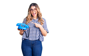 Young caucasian woman holding vintage telephone smiling happy pointing with hand and finger