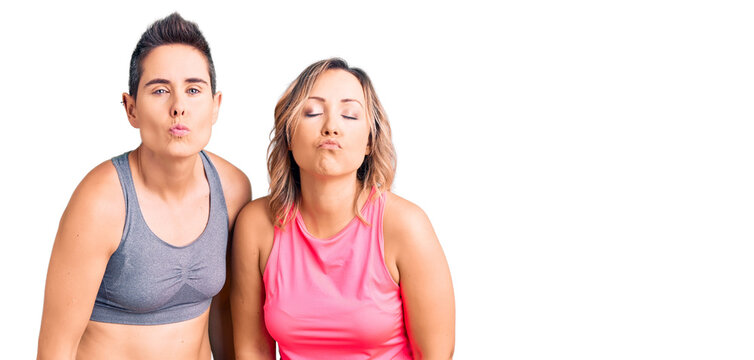 Couple of women wearing sportswear looking at the camera blowing a kiss on air being lovely and sexy. love expression.